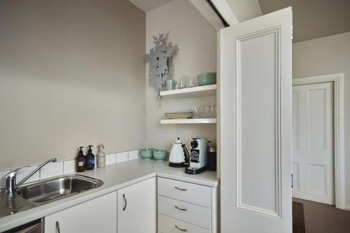 a kitchen with white cabinets and a sink and a door at Briarwood in Greytown