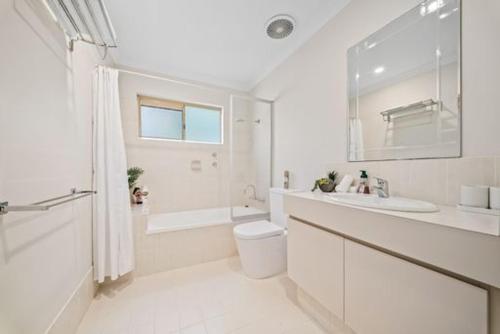 a white bathroom with a toilet and a sink at Fairway Retreat in The Vines
