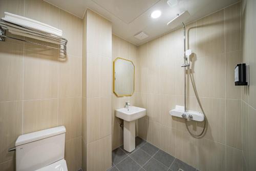 a bathroom with a sink and a toilet and a mirror at Calm Rest Hotel Masan in Changwon