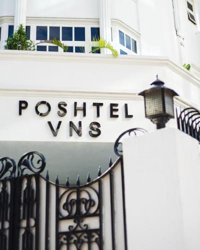 a sign on a white building with a wrought iron gate at Poshtel VNS in Varanasi