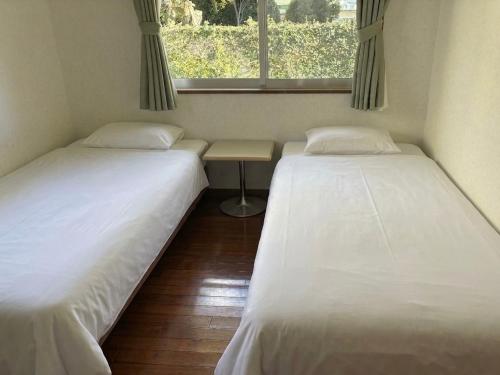 two beds in a small room with a window at 本部コテージnobaru in Motobu
