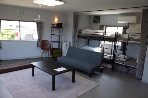 a living room with a couch and a table and bunk beds at カルフールゲストハウス別館 in Toyama