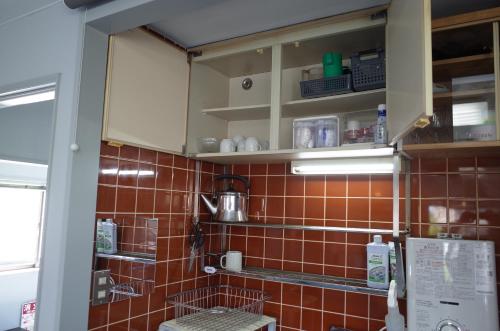 a kitchen with orange tiles on the wall at カルフールゲストハウス別館 in Toyama