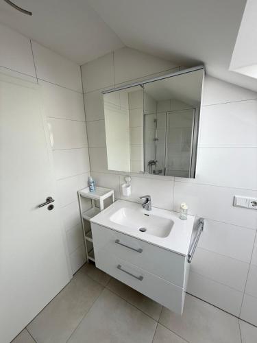 a white bathroom with a sink and a mirror at Toukam's Apartment, near Ingolstadt in Stammham