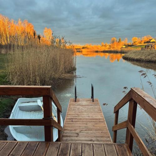 a boat sitting on the water next to a dock at Kundziņu salas in Vidriži