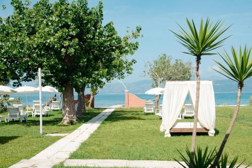 a garden with a table and chairs and the ocean at Melador beachfront studios in Kavos