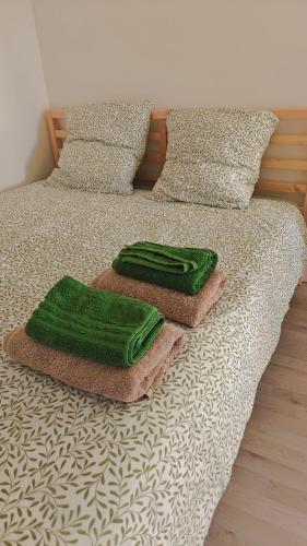 a bed with two green towels on top of it at L'orée du vignoble in Vaux-en-Beaujolais