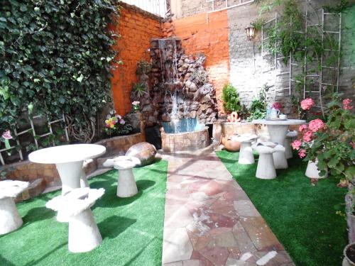 a garden with white tables and chairs and a fountain at Hotel Puno Terra in Puno