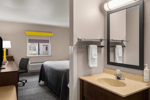 a hotel room with a bed and a sink and a mirror at Super 8 by Wyndham Kalispell Glacier National Park in Kalispell