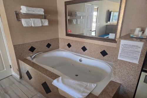 a bath tub in a bathroom with a mirror at Days Inn by Wyndham Alhambra CA in Alhambra