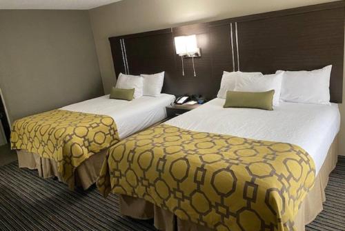 a hotel room with two beds with yellow sheets at Baymont by Wyndham Topeka in Topeka