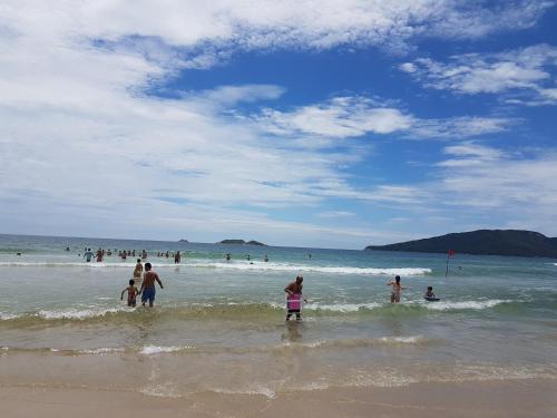 a group of people standing in the water at the beach at Apto de 02 qtos no Ingleses - Florianopolis - SC in Florianópolis