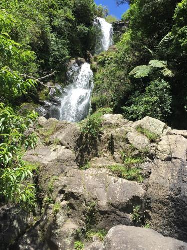 a waterfall on the side of a mountain with rocks at Warwick Hills Rural Bed & Breakfast in Papamoa