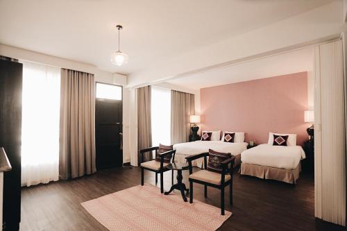 a hotel room with two beds and a table and chairs at Fullrich Lanna Suite in Chiang Mai