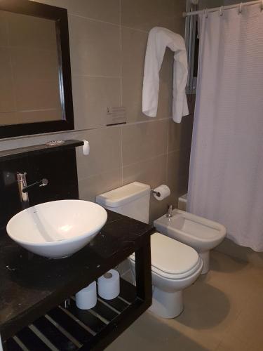 a bathroom with a sink and a toilet and a mirror at Linda Bay Resort Apt 302 in Mar de las Pampas