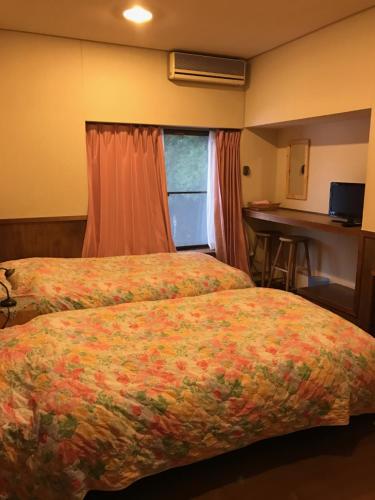 Habitación de hotel con 2 camas y mesa en North Point Lodge, en Minami Uonuma