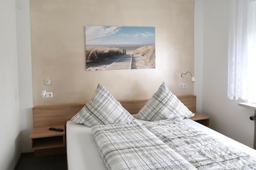 a bedroom with a bed with pillows and a picture on the wall at Pension Seehund in Norddeich in Norden