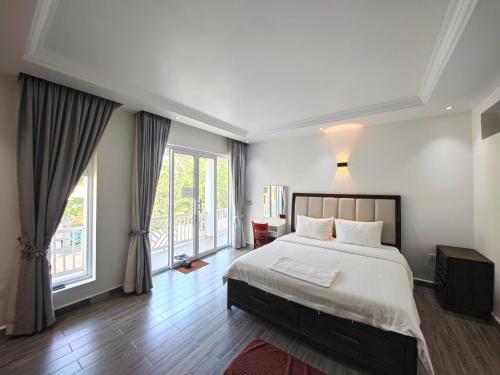a bedroom with a large bed and large windows at Kampot Origin in Kampot
