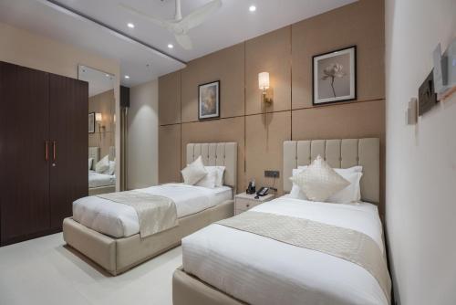 a bedroom with two beds and a mirror at Hotel Lohara Inn in Chandrapur