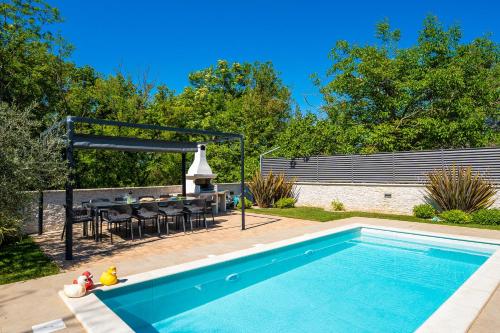 a swimming pool in a backyard with a table and a grill at Modern Villa with Pool and Wellness in Sveti Vid-Miholjice