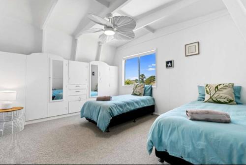 a bedroom with two beds and a ceiling fan at Pet friendly100m to Beach and Cafe by Custom Bnb Hosting in Urangan