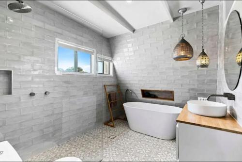 a white bathroom with a tub and a sink at Pet friendly100m to Beach and Cafe by Custom Bnb Hosting in Urangan