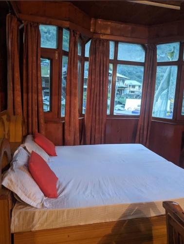 a bed with two red pillows in a room with windows at lake view resort kafnoo in Yangpa