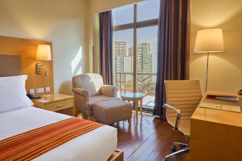a hotel room with a bed and a chair and a window at Ramada Addis, Addis Ababa in Addis Ababa