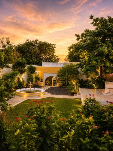 a house with a garden with a fountain and flowers at AM Hotel Kollection- Maangarh, Ratlam in Sailāna