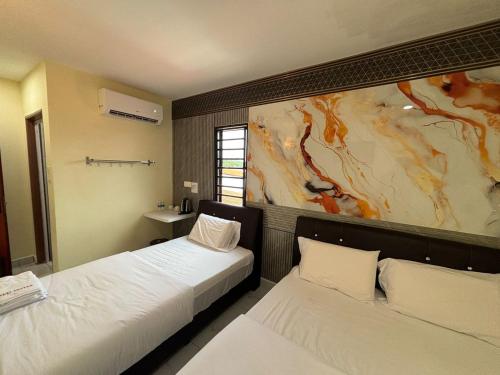 two beds in a room with a painting on the wall at Collection O Near Sunway Karnival Mall Formerly Rest Haven in Bukit Mertajam