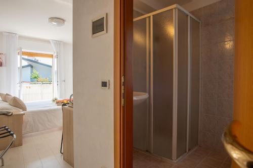 ein Badezimmer mit Dusche und ein Bett in einem Zimmer in der Unterkunft Hotel Eliani in Grado