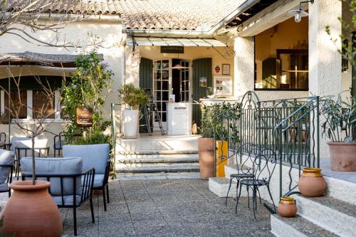 a porch of a house with chairs and tables at Hôtel La Garrigue & Bar Le Perchoir in Venasque