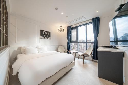 a white bedroom with a bed and a window at Hotel Lassa in Seoul