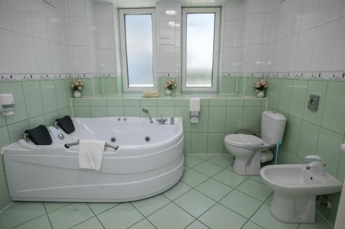a bathroom with a tub and a toilet and a sink at Hotel Senator in Slatina
