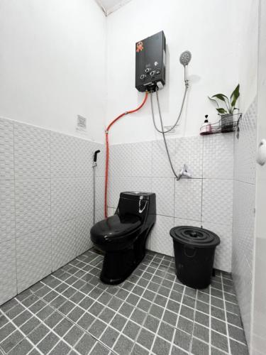 a bathroom with a black toilet in a room at SleepOver BDI2 in Wonosobo