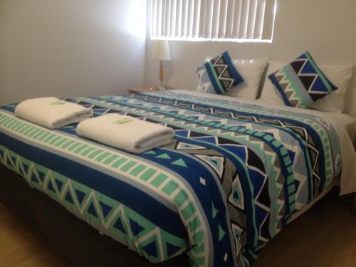 two beds with blue and white pillows in a room at Mandurah Ocean Marina Chalets in Mandurah