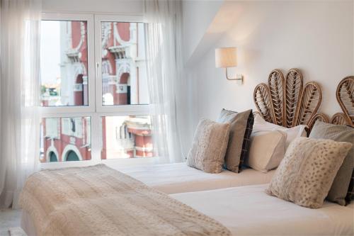 a white bedroom with a bed and a window at Apartamento Platas Centro in Ribadesella