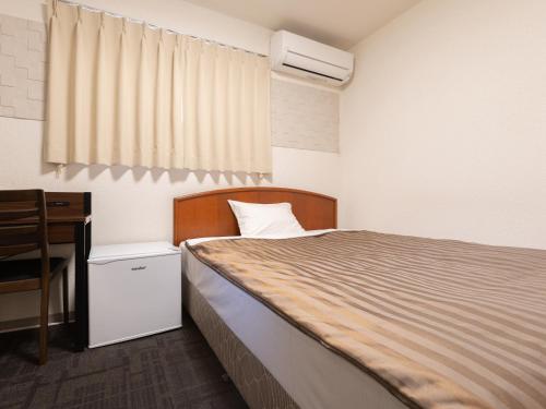 a bedroom with a bed and a desk and a window at Itoen Hotel Hakone Yumoto in Hakone
