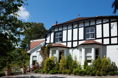 a white and black house with trees and plants at Tir y Coed Country House in Conwy