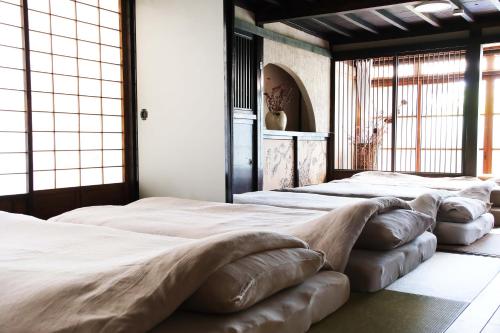 a row of beds in a room with large windows at Entire Traditional House, Pet Friendly,貸切古民家,最大9名,ペット可, 長野岡谷IC5分,ファミリー歓迎 in Okaya