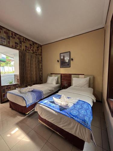 a bedroom with two beds and a window at Hotel Prima Asri 153 in Batu