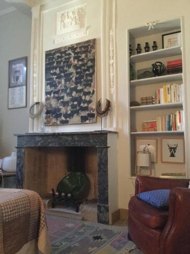 a living room with a fireplace and a chair at Hotel Les Templiers in Aigues-Mortes