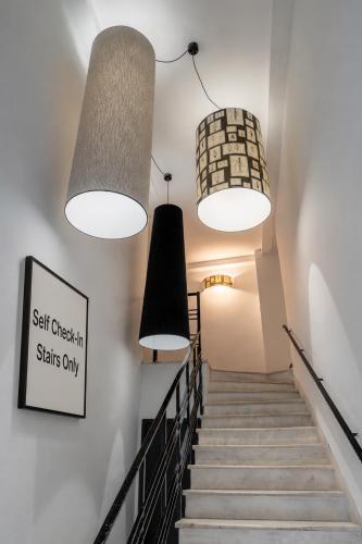 a staircase with three lights and a sign on the wall at Garment District Suites in Athens
