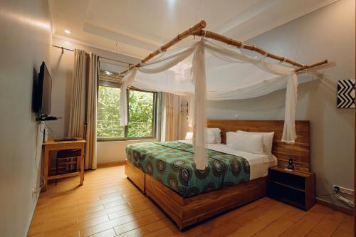 a bedroom with a canopy bed and a television at Heaven Boutique Hotel in Kigali
