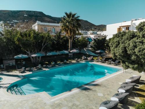 a pool at a hotel with chairs and palm trees at Polos Hotel Paros by GHH in Parikia