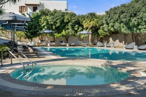 a large swimming pool with chairs and umbrellas at Polos Hotel Paros by GHH in Parikia