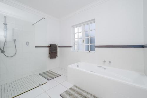 a white bathroom with a tub and a window at Greenhill Farm Cape Dutch Cottage Plettenberg Bay - 1 Bedroom Private Cottage in Plettenberg Bay
