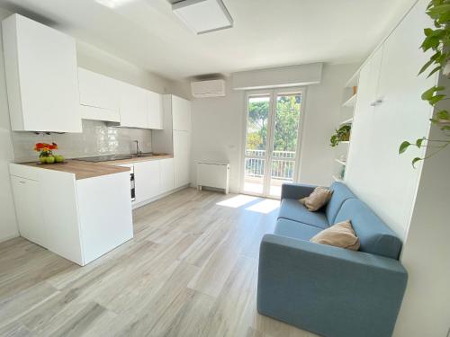 a living room with a blue couch and a kitchen at Studio Artemisia in Grado