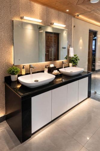 a bathroom with two sinks and a large mirror at Hotel Belvior Estate in Srinagar