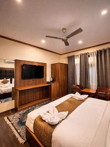 a hotel room with a bed and a flat screen tv at Hotel Belvior Estate in Srinagar